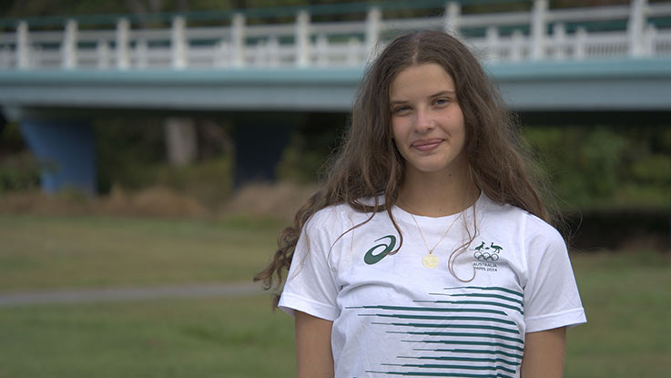 a girl wearing a white t shirt with stripes standing and smiling