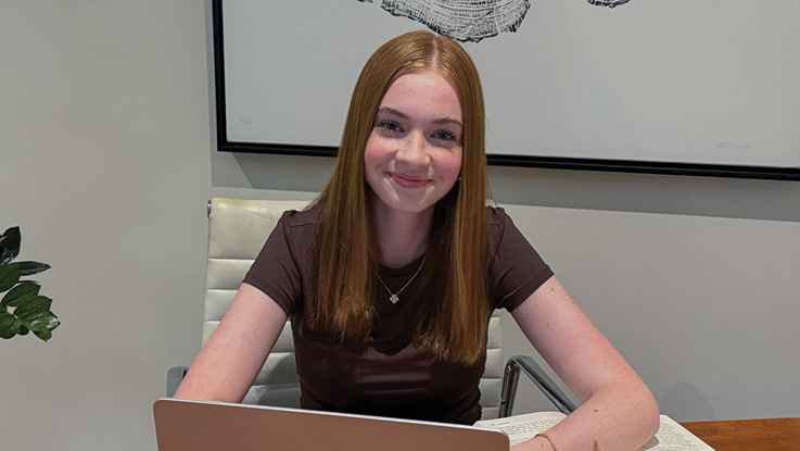 a young woman in front of a laptop smiling