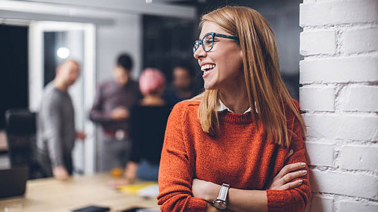 woman wearing an orange sweater smiling to the side