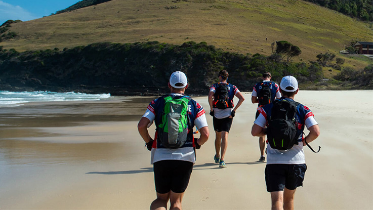 a group of runners running along the beach