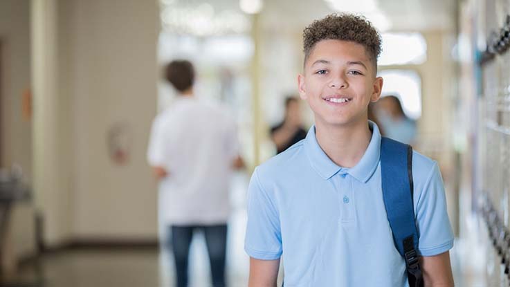 a school boy standing by lockers in a school hallway