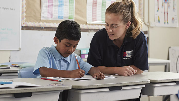 Boy sitting at desk with teacher