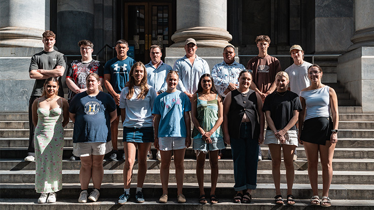 a group of indigenous youth standing on a set of steps posing together