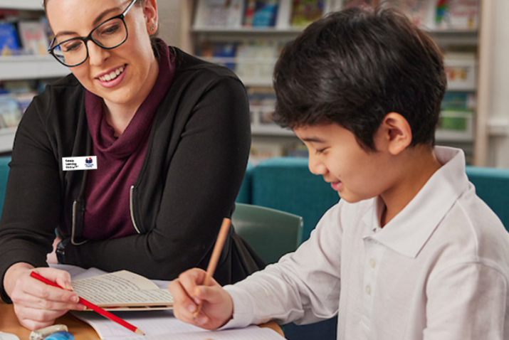Teacher sitting with student helping with school work