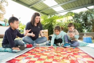 Children learning literacy and numeracy through board games with an educator through The Smith Family programs