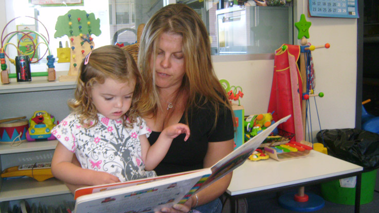 Mother and daughter sitting in a chair reading