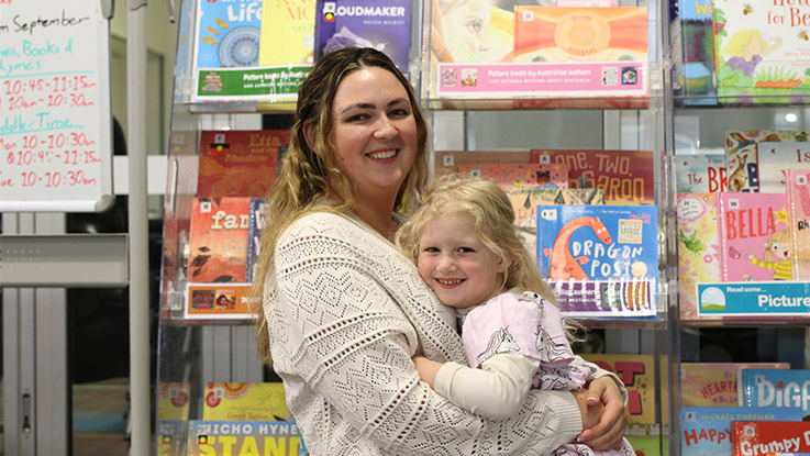 a woman posing with her young daughter smiling