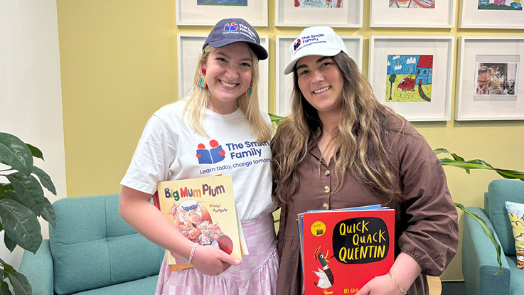 two ladies wearing the smith family caps holding childrens books