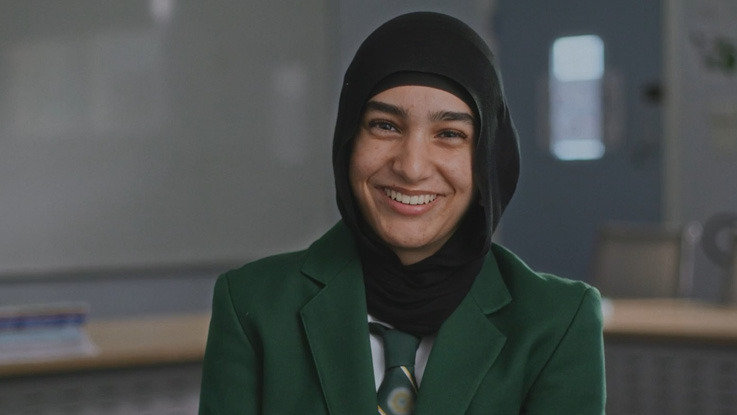 a young school student wearing a green blazer