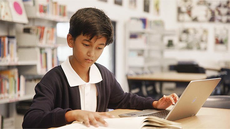 a primary school student working on his laptop